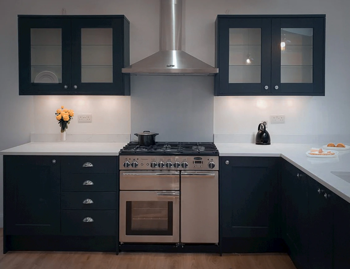 Shaker style kitchen in a midnight blue, there is a vase of yellow flowers on the white work surface