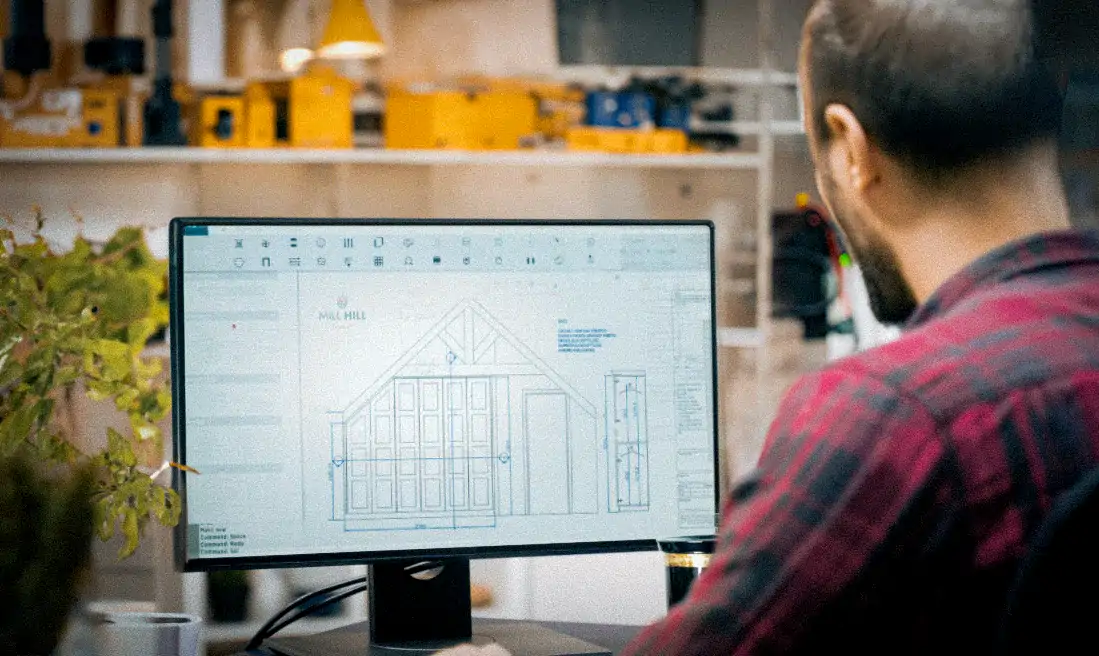 A Man in a red and black shirt working on design for a wardrobe on a computer screen